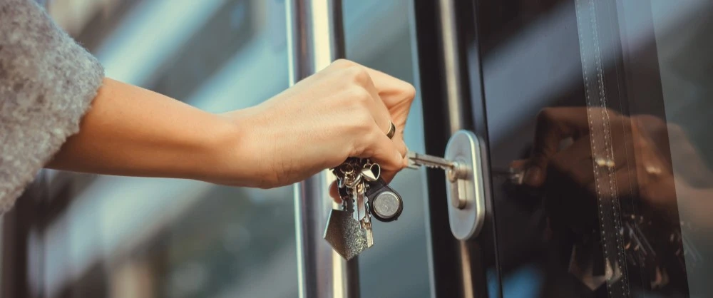 A person unlocking a door with a key