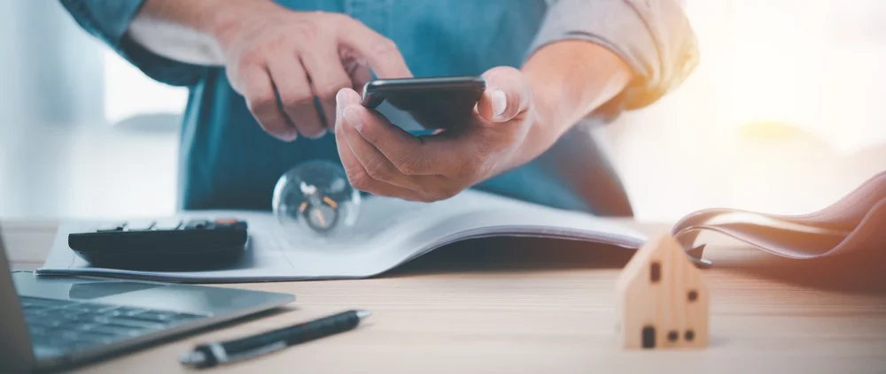 Man using cellphone at desk to do real estate